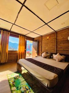 Un dormitorio con una cama grande con una ventana grande. en Bamboo Junction Resort - Kanatal, Valley & Mountain View, en Dhanaulti