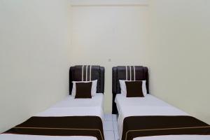 two beds in a room with black and white at Hotel O Pekanbaru near Mall Ciputra Seraya formerly Lotus Inn in Pekanbaru