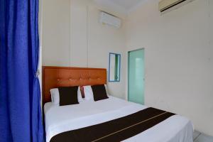 a bedroom with a large bed with blue curtains at Hotel O Pekanbaru near Mall Ciputra Seraya formerly Lotus Inn in Pekanbaru +38 photos