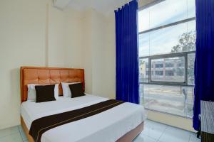 a bedroom with a bed and a large window at Hotel O Pekanbaru near Mall Ciputra Seraya formerly Lotus Inn in Pekanbaru