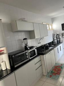 Piranhas casa de temporada في ببرانا: مطبخ بدولاب أبيض وميكرويف أسود