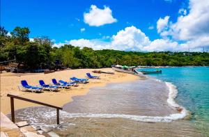 a group of chairs on a beach with a boat at El Neptuno Residencial, Sosua in Sosúa
