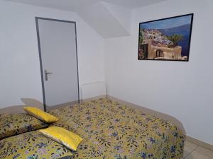 a bed with yellow pillows and a picture on the wall at le Cocon in Montgardin