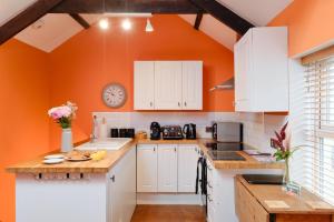 een keuken met witte kasten en een oranje muur bij Finest Retreats - The Barn at St Just in St Just