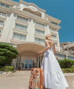 La Boutique Hotel & Suites - Adults Only في أنطاليا: امرأة ترتدي ثوب أبيض مع حقيبة