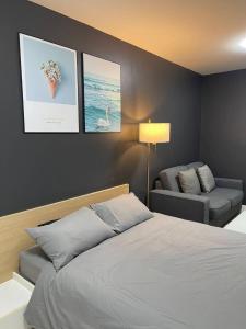 een slaapkamer met een bed en een bank en foto's aan de muur bij studio123 at Changwattana in Ban Bang Phang +6 foto's