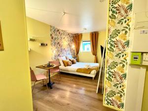 une chambre avec un lit et une table dans une pièce dans l'établissement la bonbonnière Jaune, à Caen