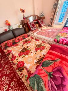 a bedroom with two beds with red and pink blankets at Habib Guest House GULMARG 11 in Tangmarg