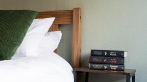a stack of books on a table next to a bed at Spacious Canalside Cottage - Games Room - Dog Walks in Loughborough