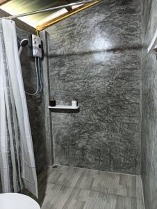 een badkamer met douche met een stenen muur bij Bansuan Lanta Maikaew in Koh Lanta