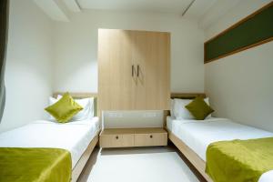 Sasya Elegance - A Boutique Hotel في Lingampalli: سريرين في غرفة صغيرة مع ملاءات خضراء