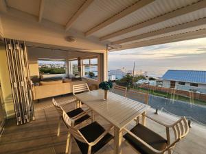 Seegeluk, magnificent beach house in De Kelders في دو كيلدرز: طاولة وكراسي خشبية على شرفة مطلة