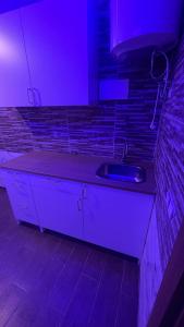 uma cozinha com um lavatório e uma luz roxa em Suits Mirasol em Tânger