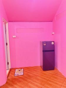 a room with a pink wall and a refrigerator at Pizza classic resort kohjum in Ban Ko Phrao