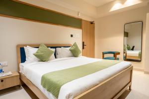 Sasya Elegance - A Boutique Hotel في Lingampalli: غرفة نوم بها سرير كبير ومرآة +صورتان