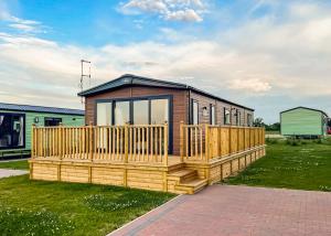 Una pequeña casa con una terraza de madera sobre el césped. en Holderness Country Park, en Tunstall