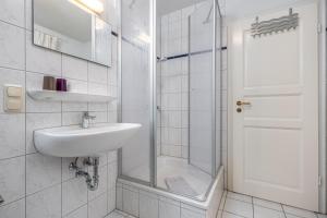 a white bathroom with a sink and a shower at Reihenendhaus Celebes in Dierhagen