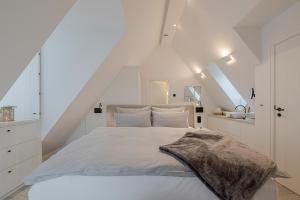 een witte slaapkamer met een groot bed met witte muren bij Sylter Strandholz in Westerland
