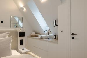 a white bathroom with a sink in a attic at Sylter Strandholz in Westerland +58 photos