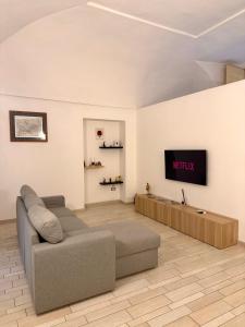 ein Wohnzimmer mit einem Sofa und einem Fernseher an der Wand in der Unterkunft Domus Gazzara -Napoli Centro Storico in Neapel + 11 Fotos