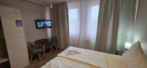 een hotelkamer met een bed, een tafel en een televisie bij Pension M in Neurenberg