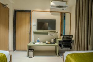 Sasya Elegance - A Boutique Hotel في Lingampalli: غرفة في الفندق بها مكتب وتلفزيون في الغرفة