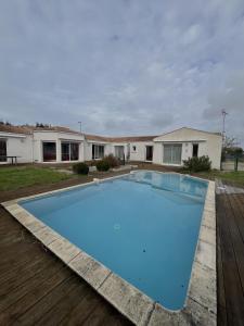 une grande piscine bleue devant une maison dans l'établissement Villa Oyala avec piscine, spacieuse et de qualite, à Saint-Pierre-dʼOléron