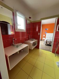 une salle de bain avec deux lavabos et un miroir et un lit dans l'établissement Villa Oyala avec piscine, spacieuse et de qualite, à Saint-Pierre-dʼOléron