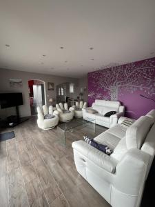 un salon avec des canapés blancs et un mur violet dans l'établissement Villa Oyala avec piscine, spacieuse et de qualite, à Saint-Pierre-dʼOléron