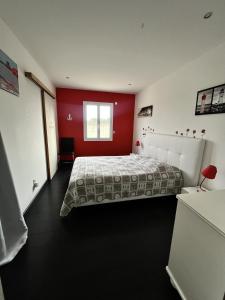une chambre avec un lit et un mur rouge dans l'établissement Villa Oyala avec piscine, spacieuse et de qualite, à Saint-Pierre-dʼOléron