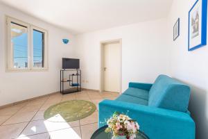 een woonkamer met een blauwe bank en een televisie bij Casa Agnese by BarbarHouse in Leuca