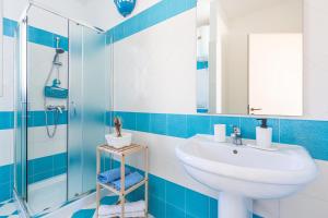 een blauwe en witte badkamer met een wastafel en een douche bij Casa Agnese by BarbarHouse in Leuca +14 foto's