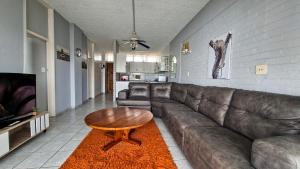 a living room with a leather couch and a coffee table at Seagull 505 in Margate +8 photos