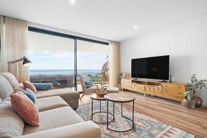 een woonkamer met een bank en een flatscreen-tv bij Peace Haven III in Câmara de Lobos