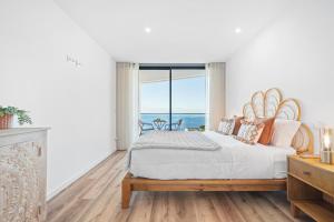 een slaapkamer met een groot bed met uitzicht op de oceaan bij Peace Haven III in Câmara de Lobos