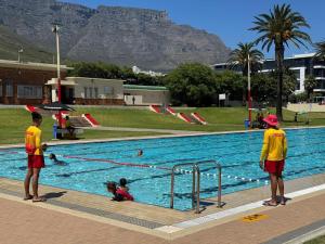 een groep mensen in een zwembad met bergen op de achtergrond bij Victorian Woodstock in Kaapstad