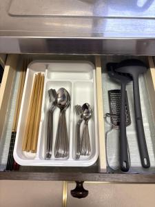 een wit dienblad met keukengerei in een lade bij Frasis in Furano