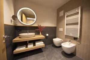 a bathroom with a sink and a toilet and a mirror at Dolomiten Apartments in Tesero +37 photos