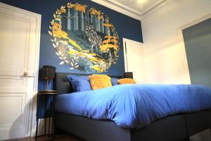 a bedroom with a blue bed with a painting on the wall at Domaine des Monts de la Baie in Mareuil-Caubert