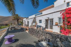 una casa bianca con un muro in pietra e un tavolo di Verde casa eden a Tías