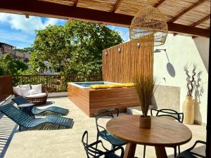 een patio met een tafel en stoelen en een hot tub bij Casa Verano - Morro de São Paulo in Morro de São Paulo