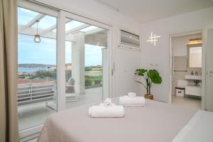 a white bedroom with a bed with two towels at Smeraldo Apartment in Palau +16 photos