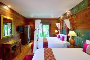 Una habitación de hotel con dos camas y un televisor. en Thai Thai Sukhothai Resort, en Sukhothai