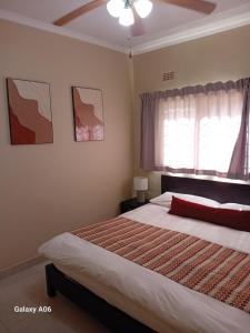 a bedroom with a large bed and a window at Victoria Apartments in Livingstone