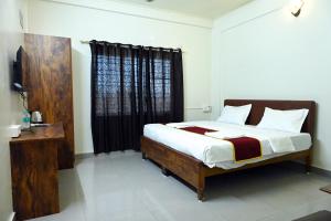 a bedroom with a bed and a window with black curtains at Hotel Sai Sagar in Manipal +7 photos