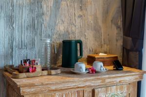 ein Holztisch mit einem grünen Krug und Tassen darauf in der Unterkunft Royal Agung Amertha Villa in Bedahulu