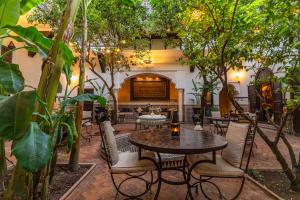 an outdoor patio with tables and chairs and trees at Riad ILayka in Marrakech