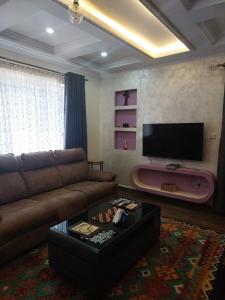 Una sala de estar con un sofá y un televisor de pantalla plana. en Yukis & Kukis Place 5 Bedrooms, en Embu