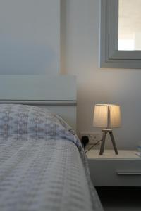 Larnaca Salt Lake Gem, Airy 2 BDRM Apartment في لارنكا: سرير عليه مصباح على طاولة بجانبه نافذة