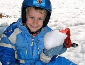 塞斯特雷Nevesestriere的一个小男孩抱着一堆雪。